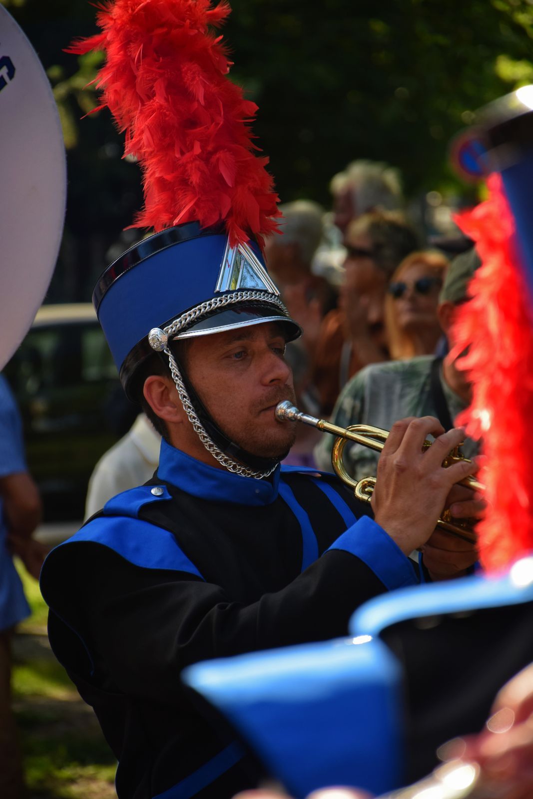 Trompettiste des Blackgames en uniforme bleu et shako à plumet rouge, jouant au plus près du public du corso