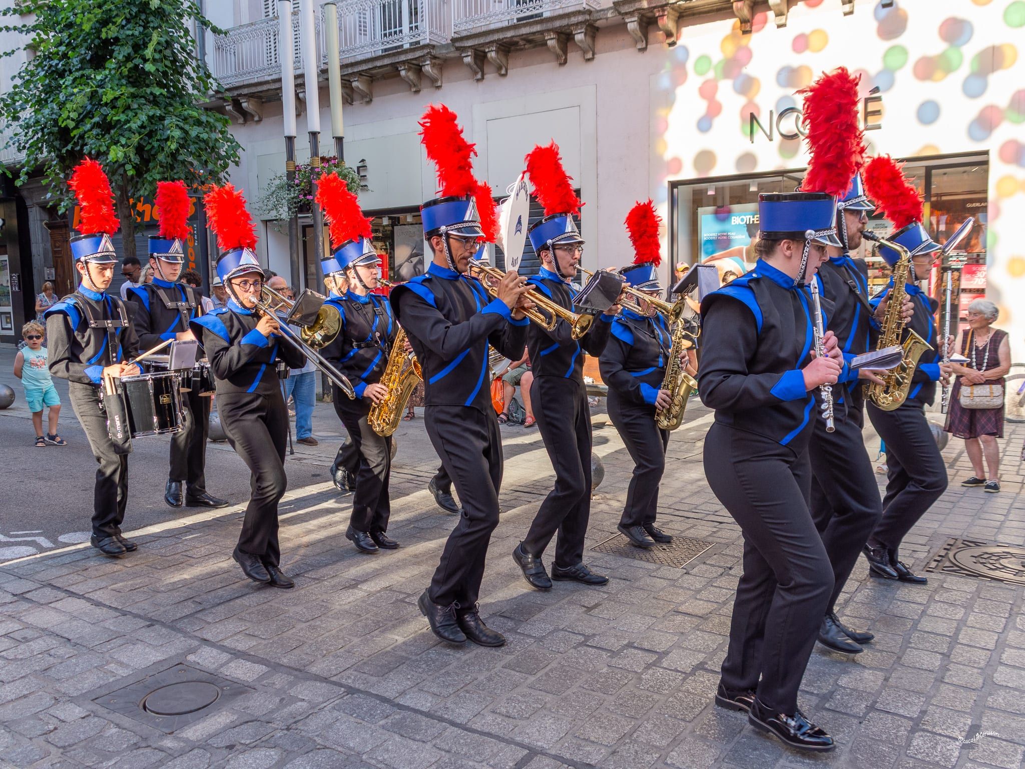 Marching Blackgames en défilé, shakos rouges et formation cuivres