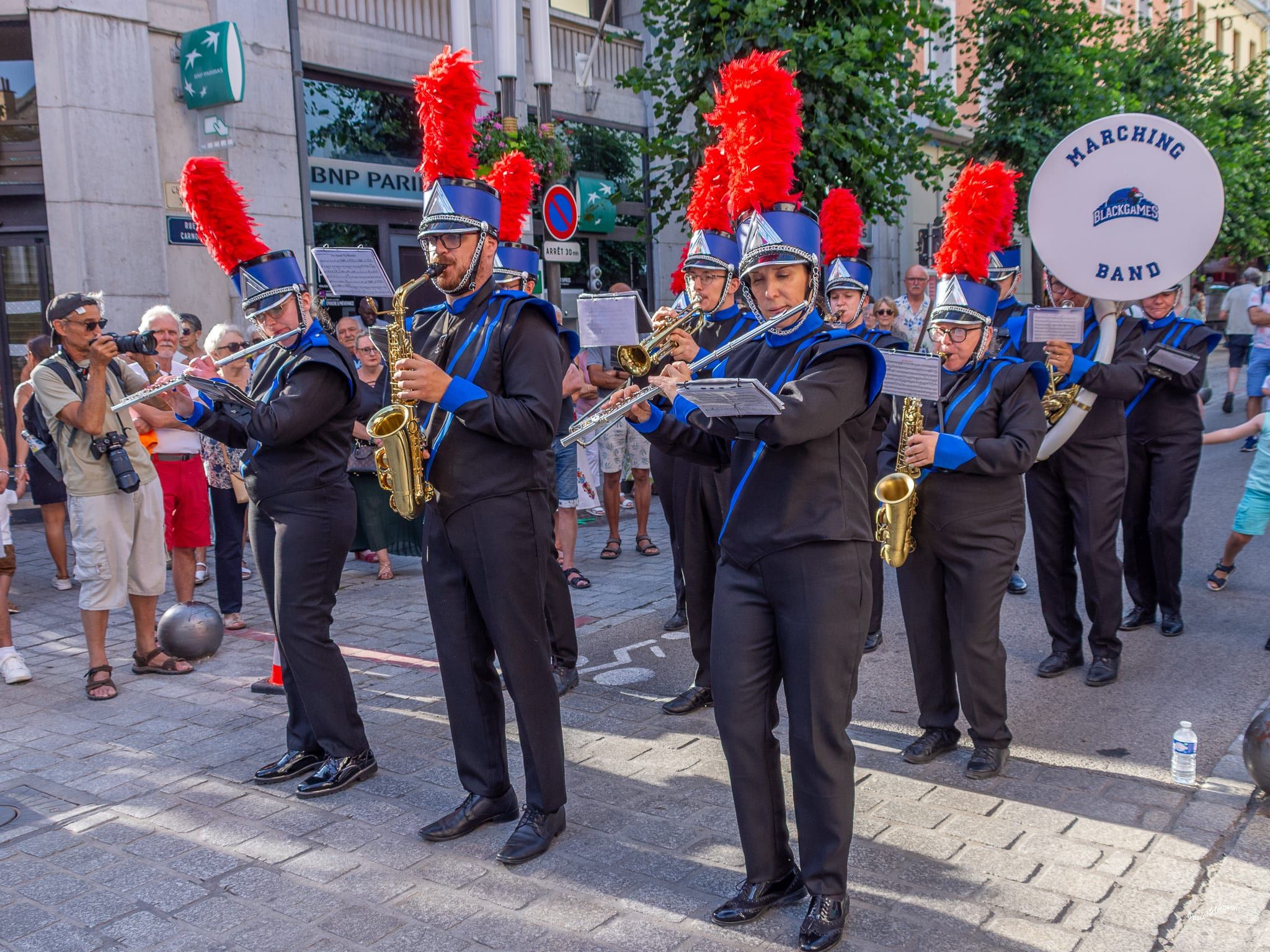Pupitre saxophones face caméra, shakos rouges et uniformes bleu et noir